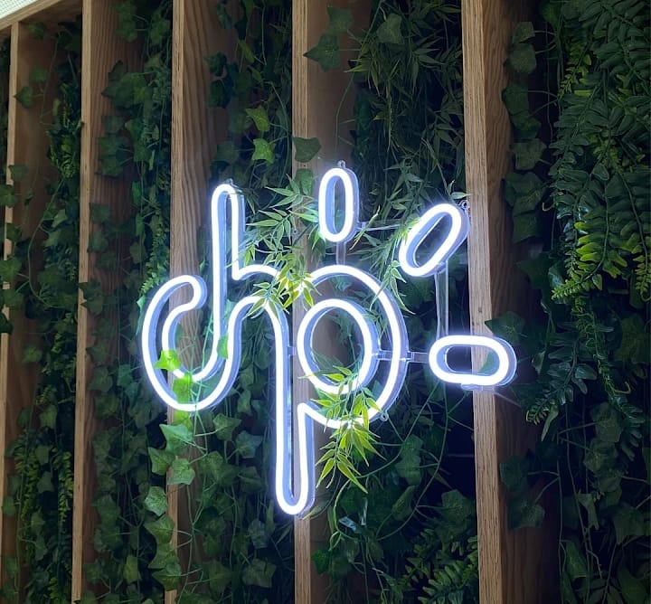 Custom white LED neon logo sign mounted on a green wall with wooden slats in Nairobi